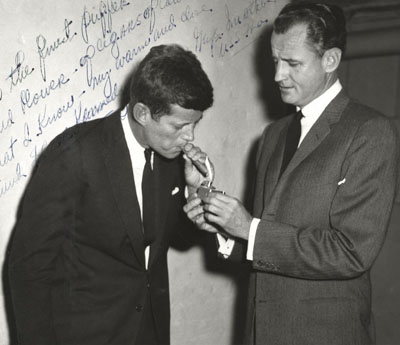 John F. Kennedy lights up cigar with his close friend Senator George Smather of Florida.